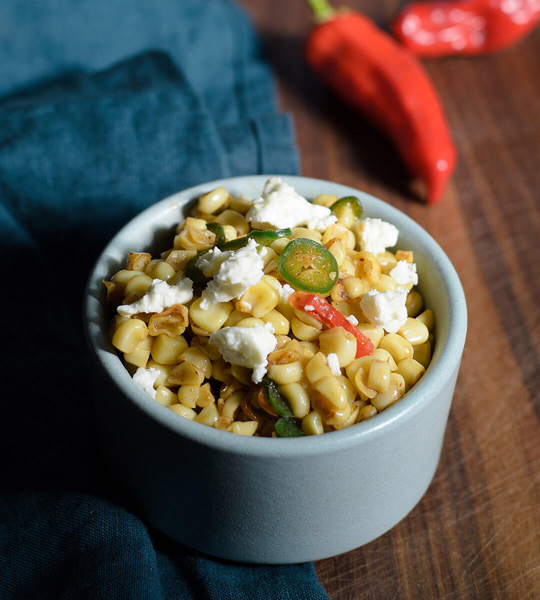 Corn salad with chili butter, peppers, and garnished with feta.
