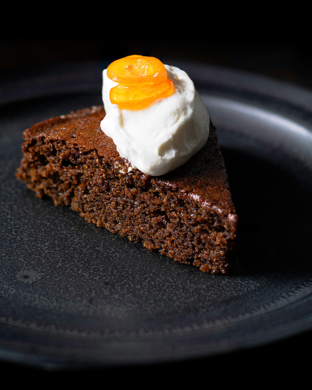 Slice of fresh ginger cake with honey whipped cream and candied kumquats.