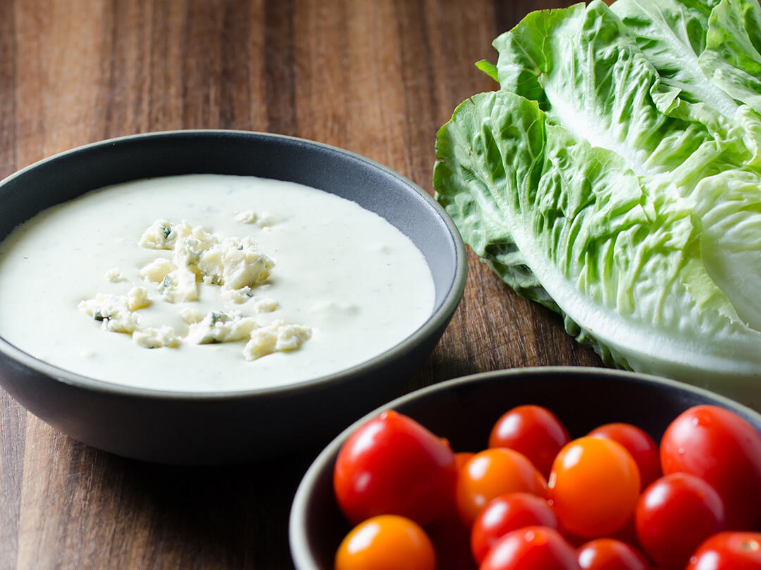 Bowl of blue cheese dressing, bowl of cherry tomatoes, little gem lettuce.